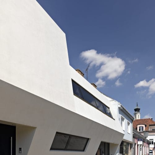 lostinarchitecture_BUR_ White Monolith_Ordination und Wohnhaus von architekturaffinen Auftraggeber:innnen, geschlossene Straßenfassade, die sich im Gehsteigbereich für den Eintritt in die Arztpraxis öffnet.