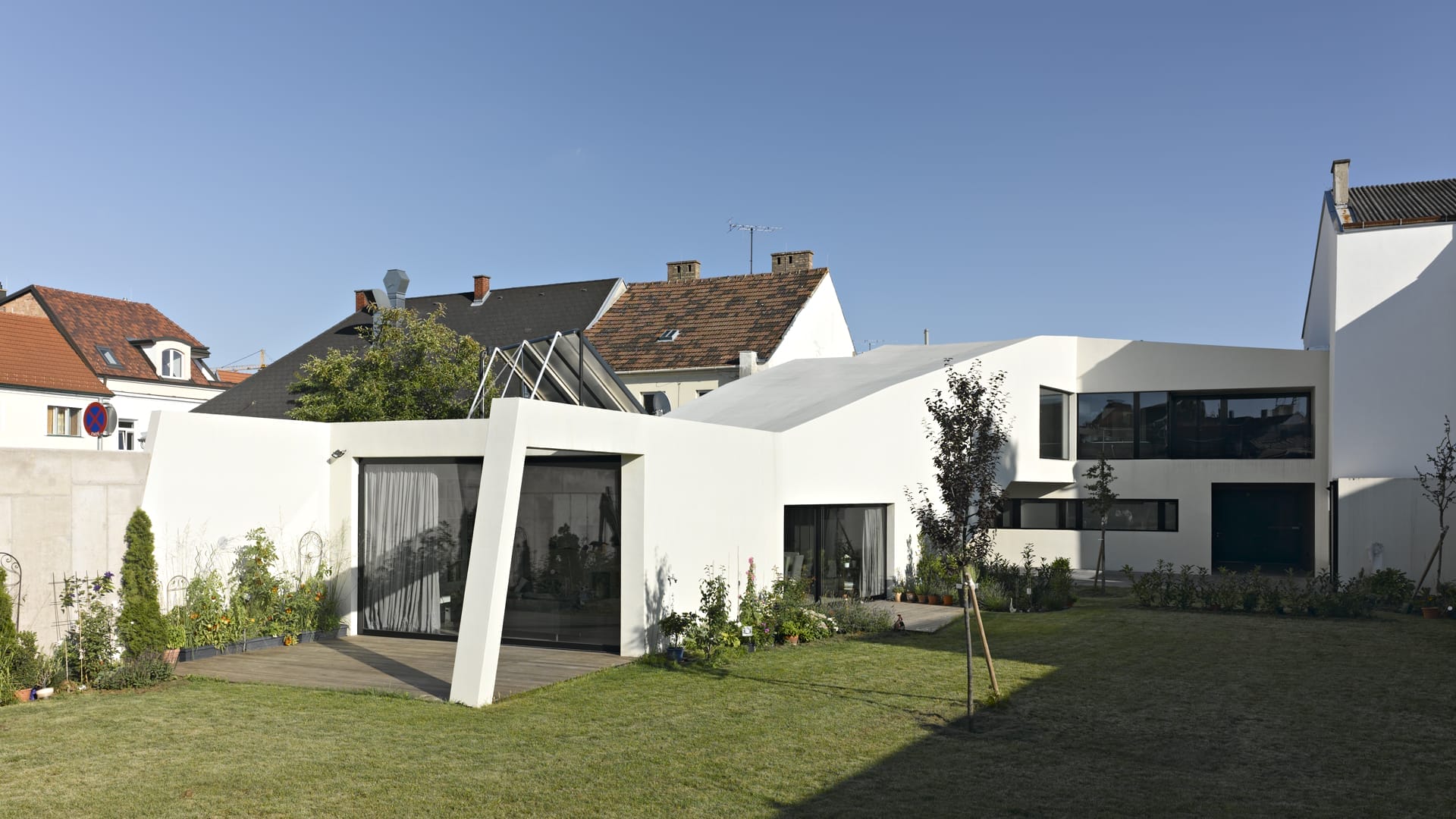 lostinarchitecture_BUR_ White Monolith_Ordination und Wohnhaus mit Garten mitten in der Stadt. Hier der Blick vom Garten auf das Gebäude, wo die totale Privatssphäre spürbar ist.